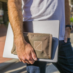 Person holding a laptop with a CIVIC Access Pouch 1L in Fossil Brown attached on a blurred outdoor background