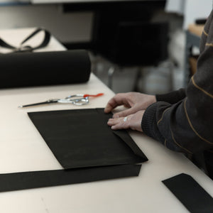 Person working with waxed canvas material on a table in a workshop setting