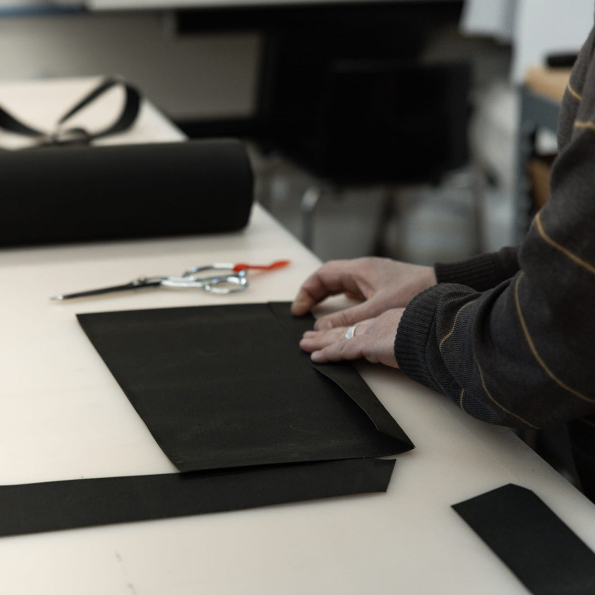 Person working with waxed canvas material on a table in a workshop setting