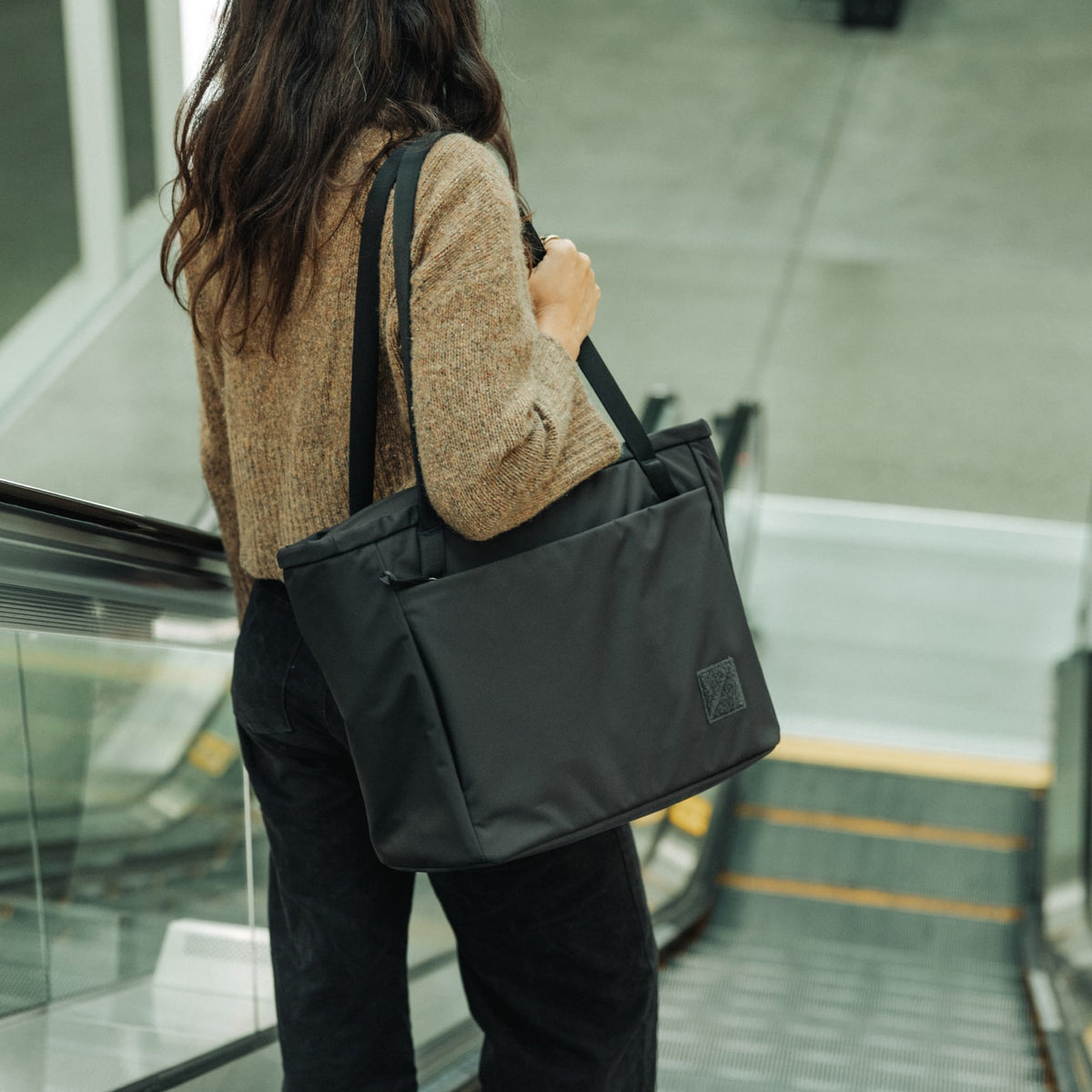 CIVIC Daily Tote 24L in Solution Dyed Black - CDT24 - shoulder carry going down escalator