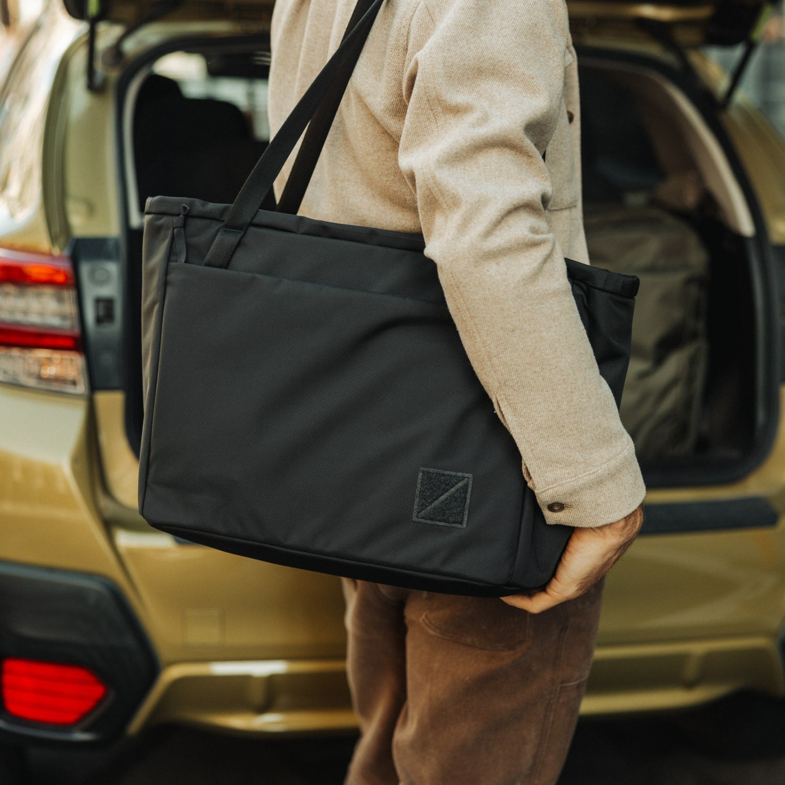 CIVIC Daily Tote 24L in Solution Dyed Black - CDT24 - holding tote by trunk of car, shoulder carry [13024a-SBK]