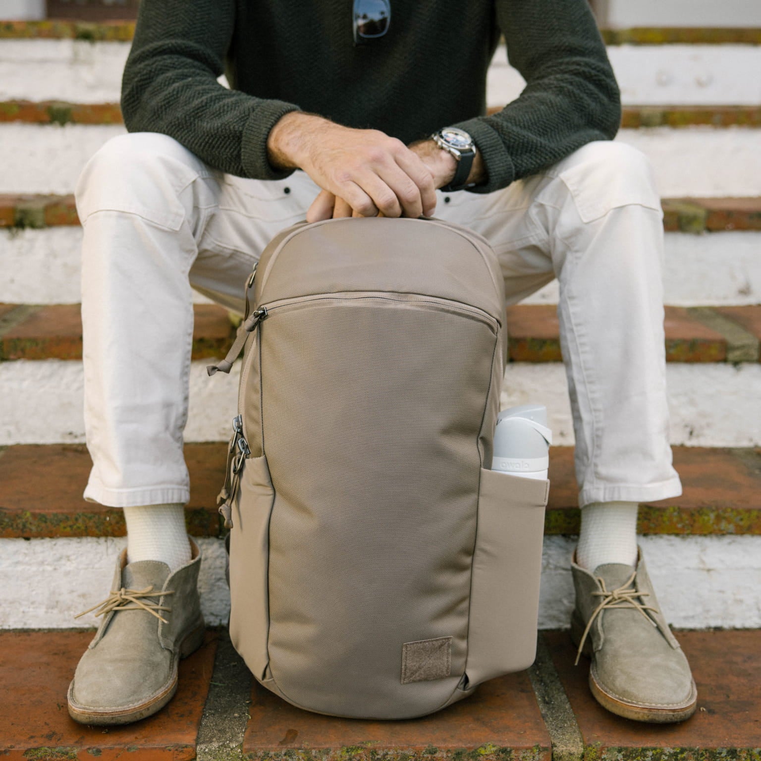 Person sitting on steps with a CIVIC Half Zip 22L in Fossil Brown backpack [13003d-FBN]