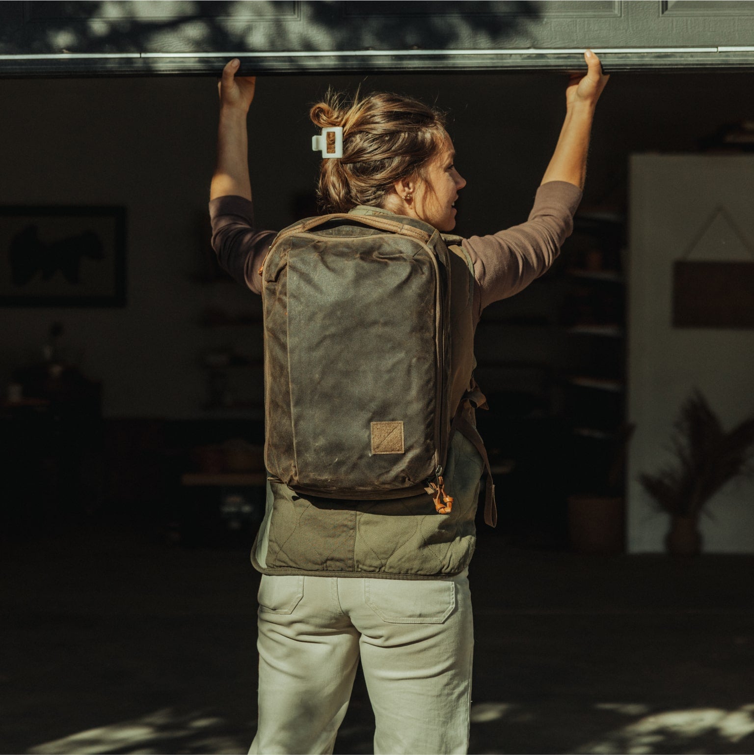 Woman wearing CIVIC Panel Loader 16L in a green vest and closing a garage door [13016cc-WTN]
