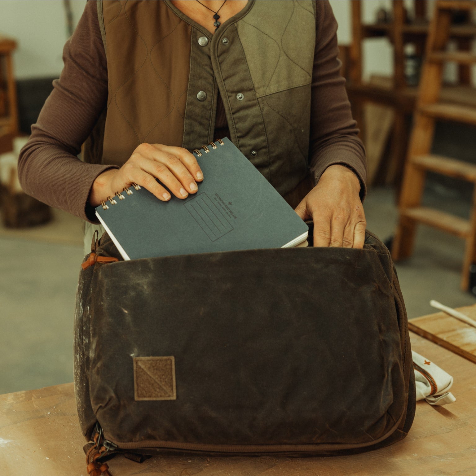 CIVIC Panel Loader 16L in waxed tan - packing the side access pocket with a notebook. [13016cc-WTN]