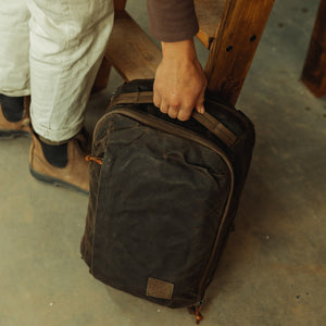 CIVIC Panel Loader 16L in waxed tan - top handle grabbed in a garage
