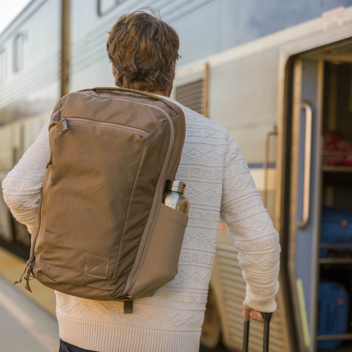 Man with a CIVIC Travel Bag 26L in Fossil Brown backpack boarding a train