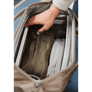 Hand reaching into a Transit Duffel 25L in Fossil Brown -  bag with compartments.