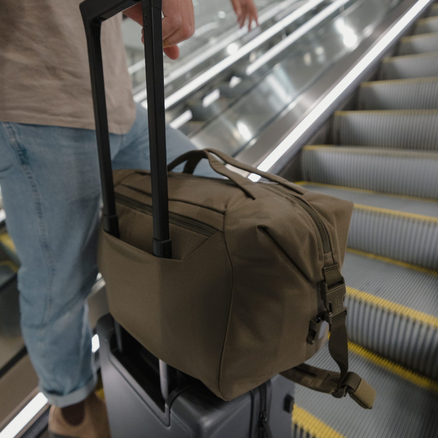 ransit Duffel 25L in OD Green on roller luggage in airport escalator [13023d-ODG]