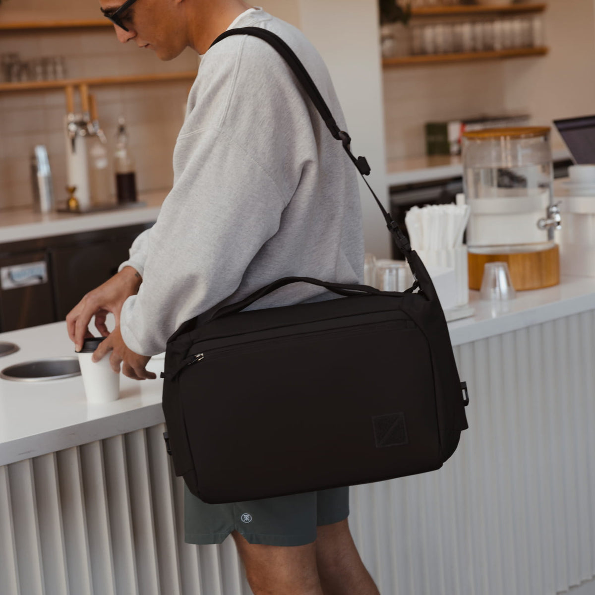 Transit Duffel 25L in Solution Dyed Black - worn in a coffee shop