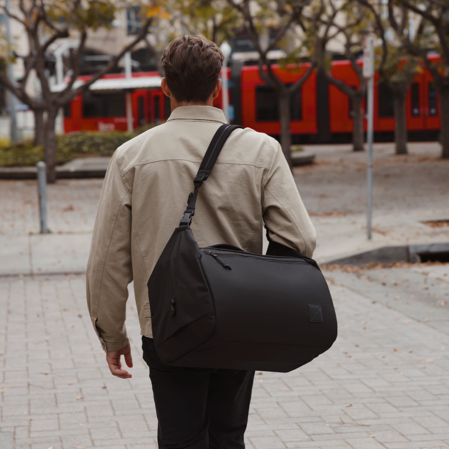 Transit Duffel 35L in Solution Dyed Black - over shoulder strap carry to train [13014d-SBK]