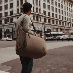 Transit Duffel 35L in Fossil Brown carried in a city