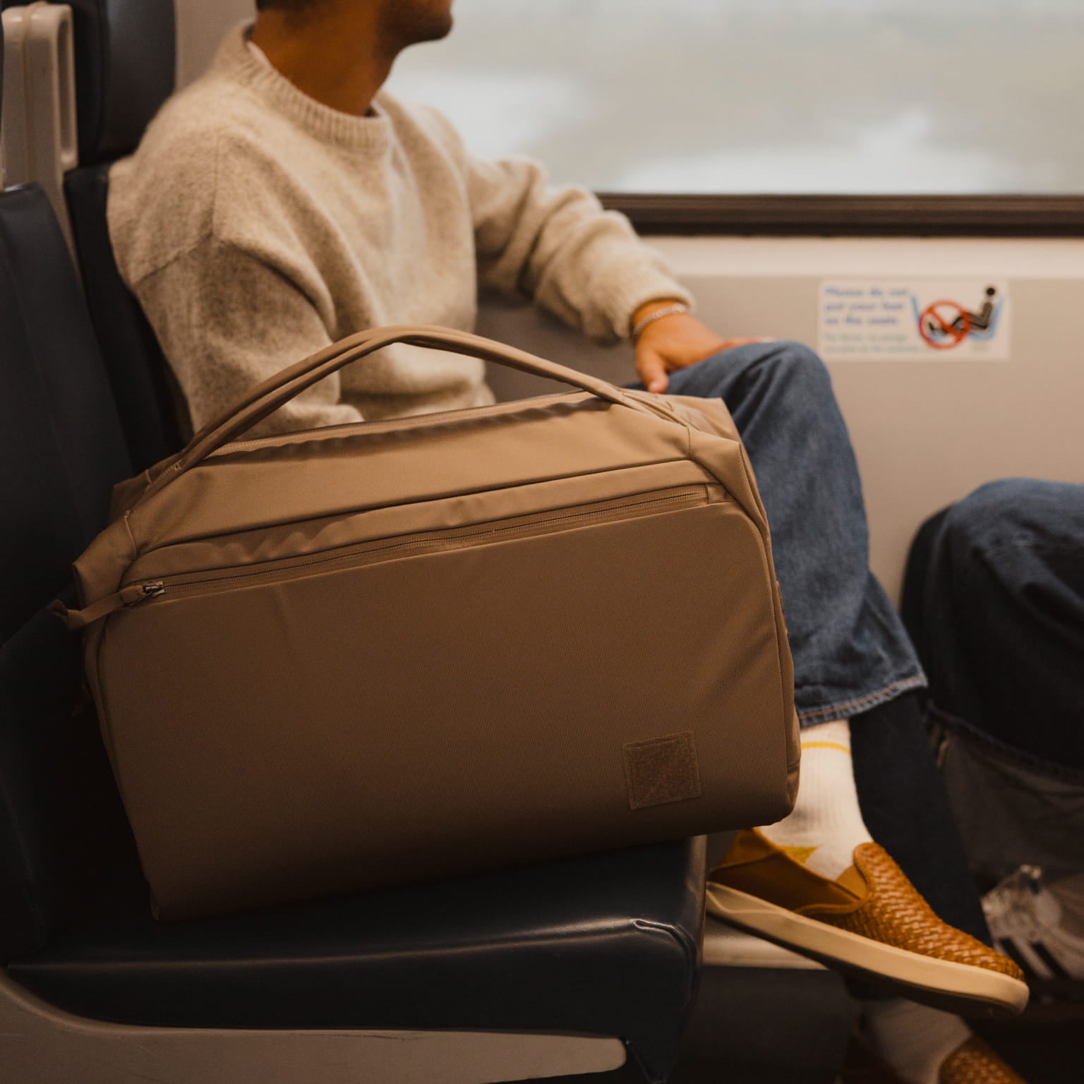 Transit Duffel 35L in Fossil Brown carried on a train [13014d-FBN]