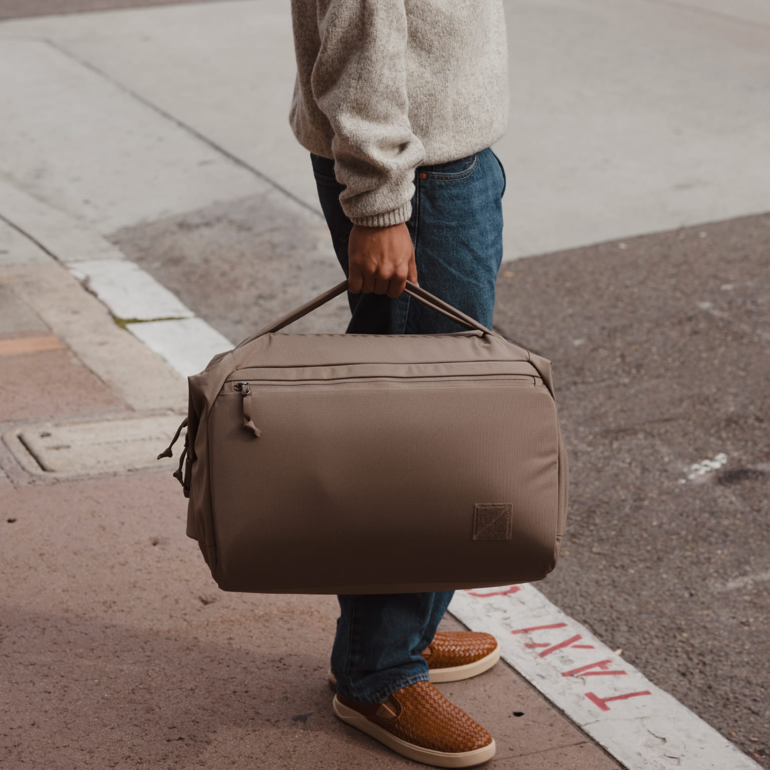 Transit Duffel 35L in Fossil Brown carried in a city by hand [13014d-FBN]