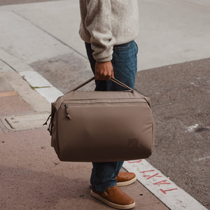 Transit Duffel 35L in Fossil Brown carried in a city by hand