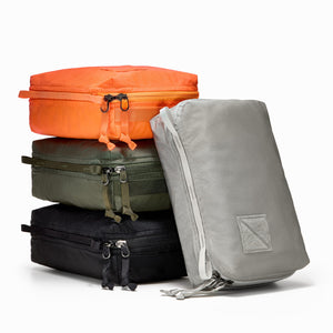 Transit Packing Cube 4L, stack of four cubes in Hot Orange, OD Green, Black, and Standard Gray