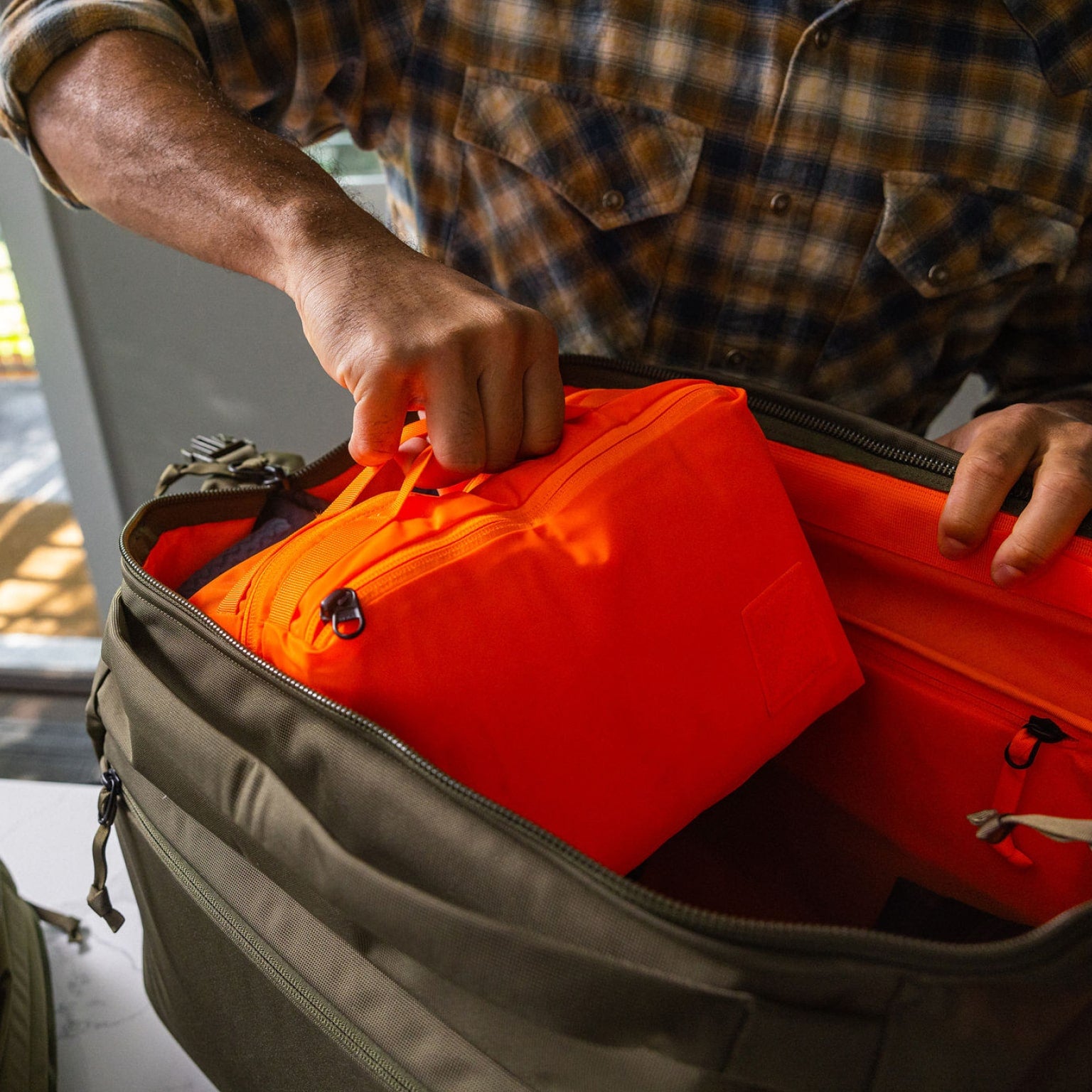 Transit Packing Cube 8L in Hot Orange coming out of Transit Duffel 35L [13015a-HTO]