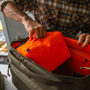 Transit Packing Cube 8L in Hot Orange coming out of Transit Duffel 35L