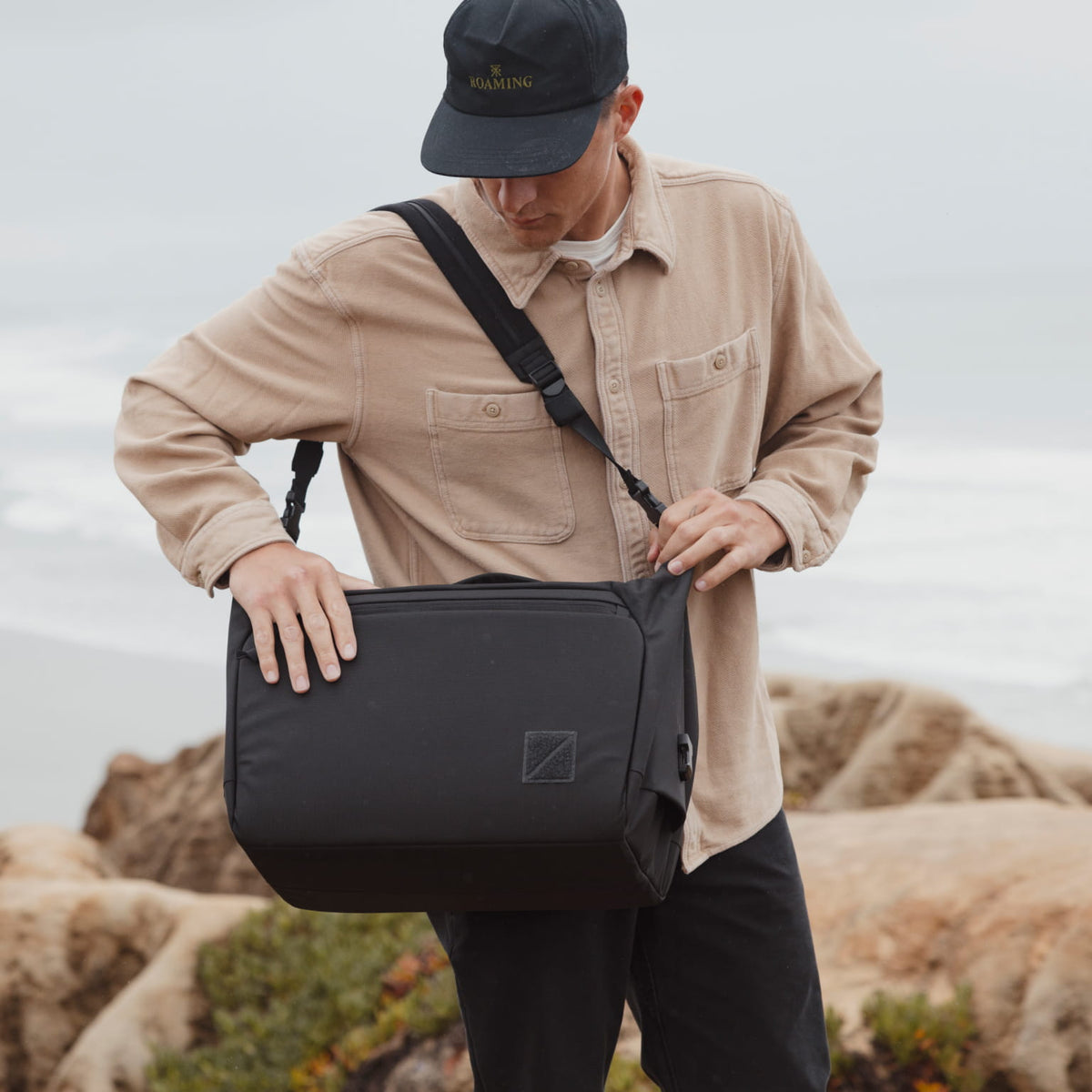 Person holding a black duffel with Transit Strap outdoors with a neutral background